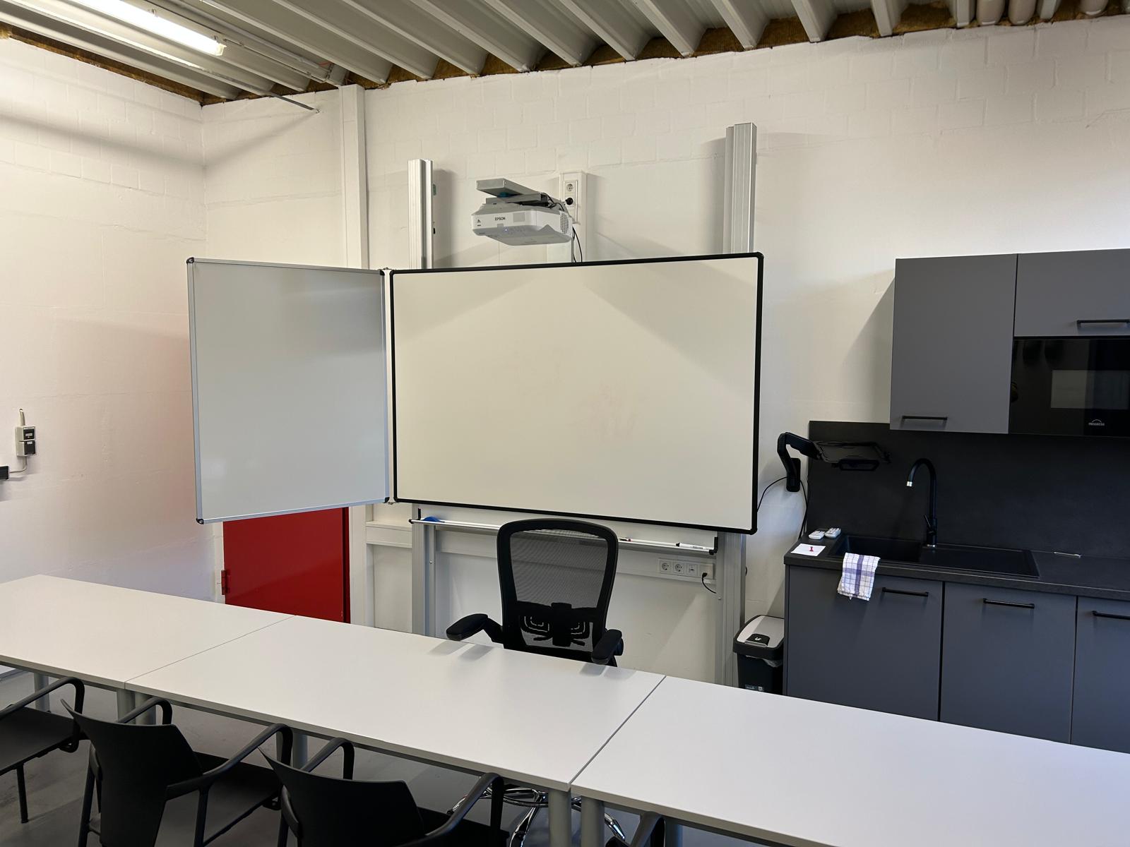 Whiteboard mit Projektionsfläche und Beamer in einem modernen Schulungsraum