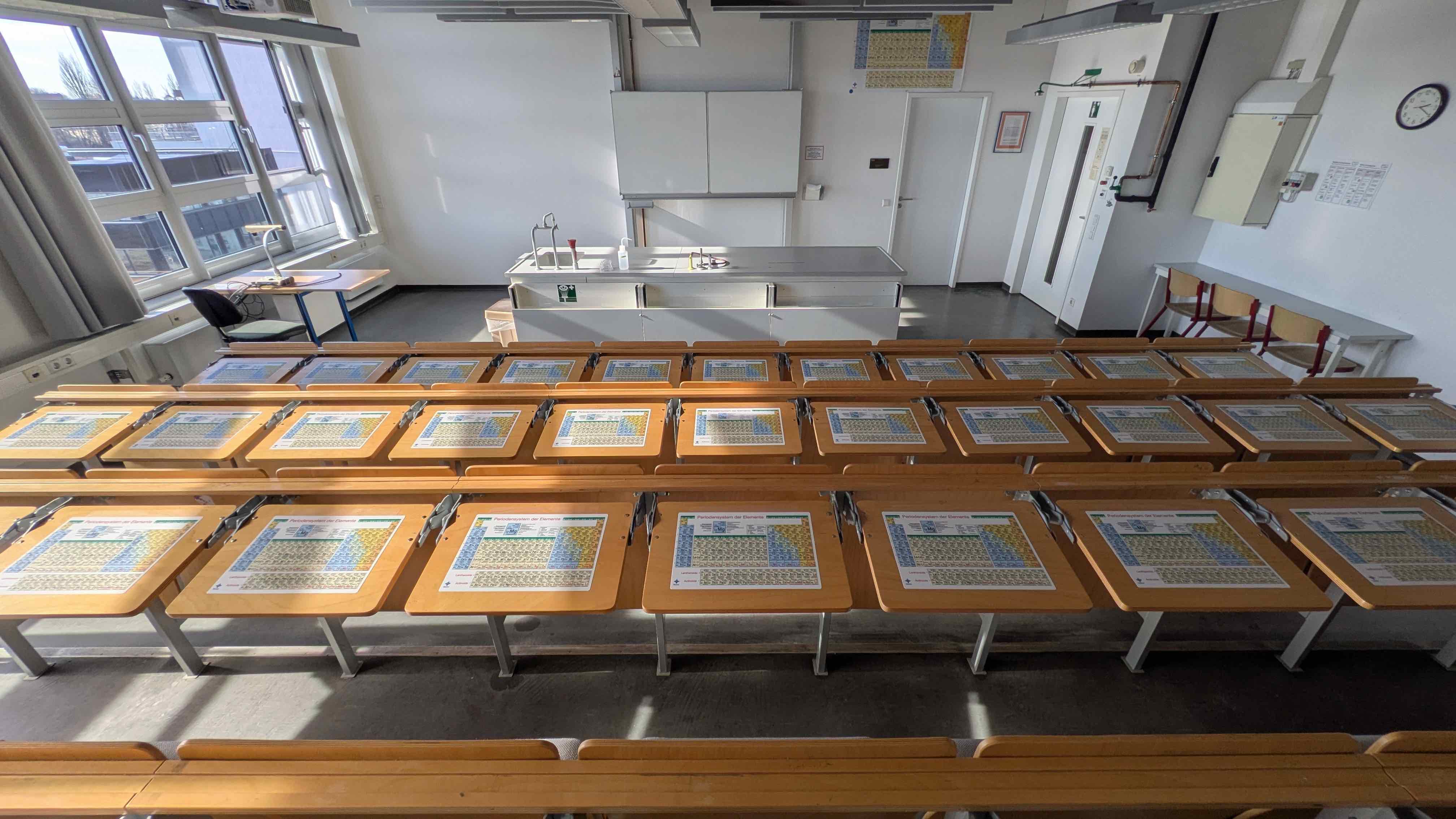 Chemie-Hörsaal mit selbstklebenden blume Periodensystem-Tischsets auf den Schülerarbeitsplätzen und Experimentiertisch im Hintergrund